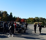 a group of golfers gathers around golf carts at course to begin day of golfing