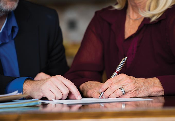 Man pointing to paper as older woman signs