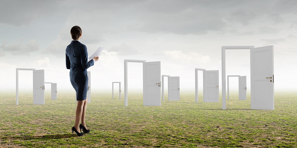 Woman standing in field looking at many opened doors