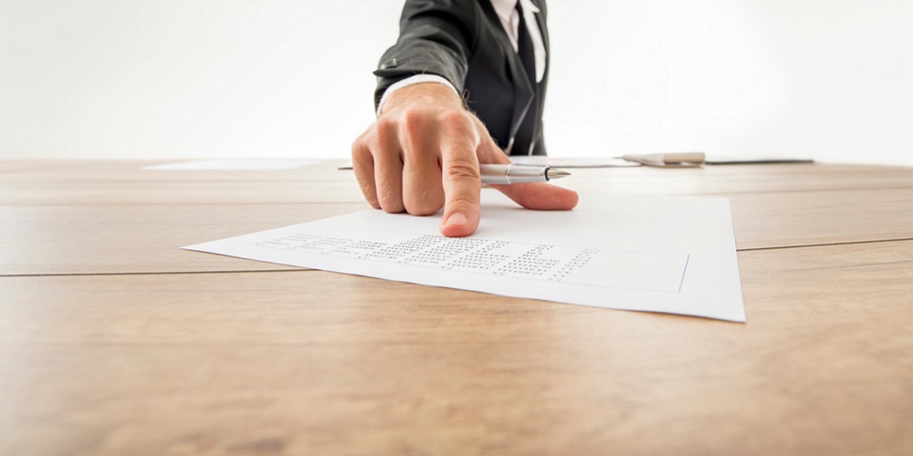 photo of male hand pointing to draft expert witness report on table