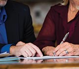Man pointing to paper as woman signs