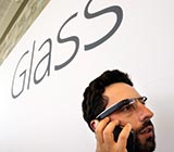 Man wearing Google glasses under a sign that reads GLASS