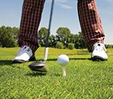 Shot of golf club, tee and ball lining up with feet in background