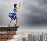 Woman blindfolded standing on the edge of the top of a building
