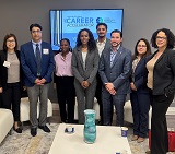 photo of OBA Career Accelerator participants, standing in OBA member lounge in front of TV screen with Career Accelerator logo