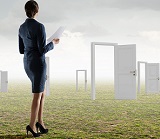 Woman standing in field looking at many opened doors