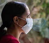 Woman with face mask looking out window