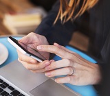 Close-up of the hands of a woman at a cafe as she scrolls through news on her phone