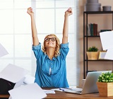 Woman at desk, arms raised in victory