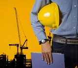 man with construction helmet under arm, construction rig in background