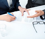 three people around desk, hands only, gesturing over a contract