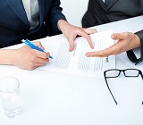 three people around desk, hands only, gesturing over a contract