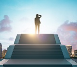 Young women in suit atop wide stairs looking out over at sunny city skyline