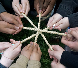 many hands of different ethnicities holding ropes together