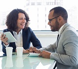 female mentor provides feedback to younger male mentee at conference table