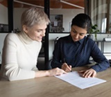 Lawyer seated at a table with client, helping them complete form