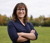 Photo of President Karen Perron in front of fall-trees