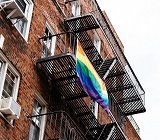 apartment building viewed from outside with PRIDE flag hanging from a window