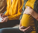 Pregnant lady sitting next to man taking notes