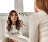 meeting between a worried-looking client and lawyer who is listening and leaning in, offering counsel