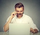 Man looking down at laptop with glasses pushed down his nose