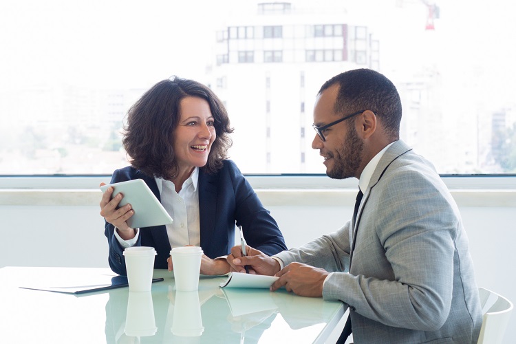 female mentor provides feedback to younger male mentee at conference table