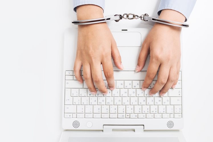 hands typing on keyboard while handcuffed