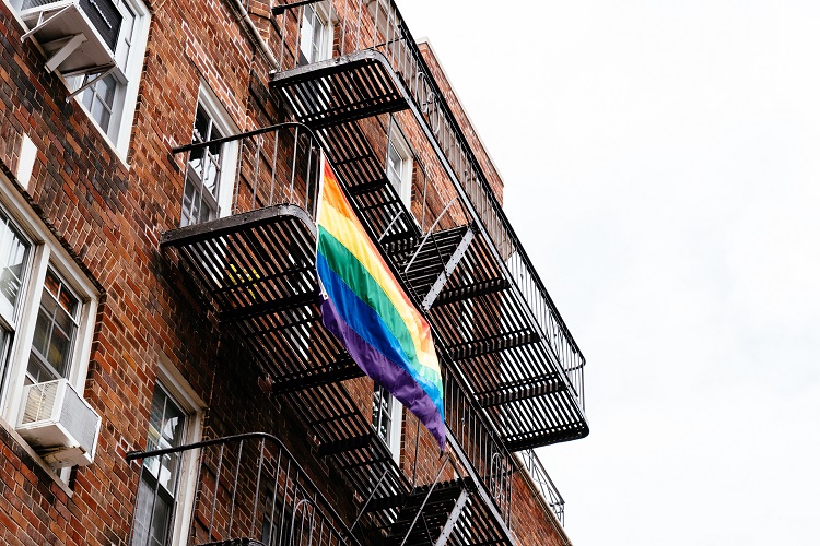 view of an apartment building from the outside with a PRIDE flagging hanging from a windo