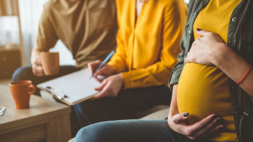 Pregnant lady sitting next to man taking notes