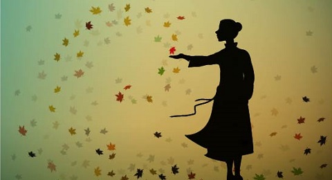 Image of a silouette of a woman standing with leaves blowing in the wind