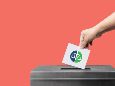Hand placing a ballot into a voting box