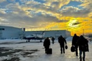 photo of passengers with suitcases crossing snowy airstrip under sunny skies with puffy clouds