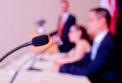Microphone with people sitting at table in background.
