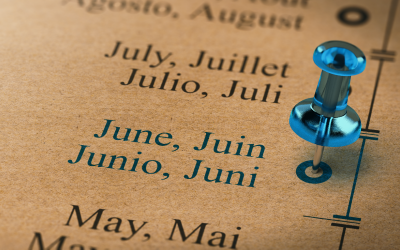 Close-up of a calendar showing the month of June highlighted with a blue pushpin, with month names in multiple languages.
