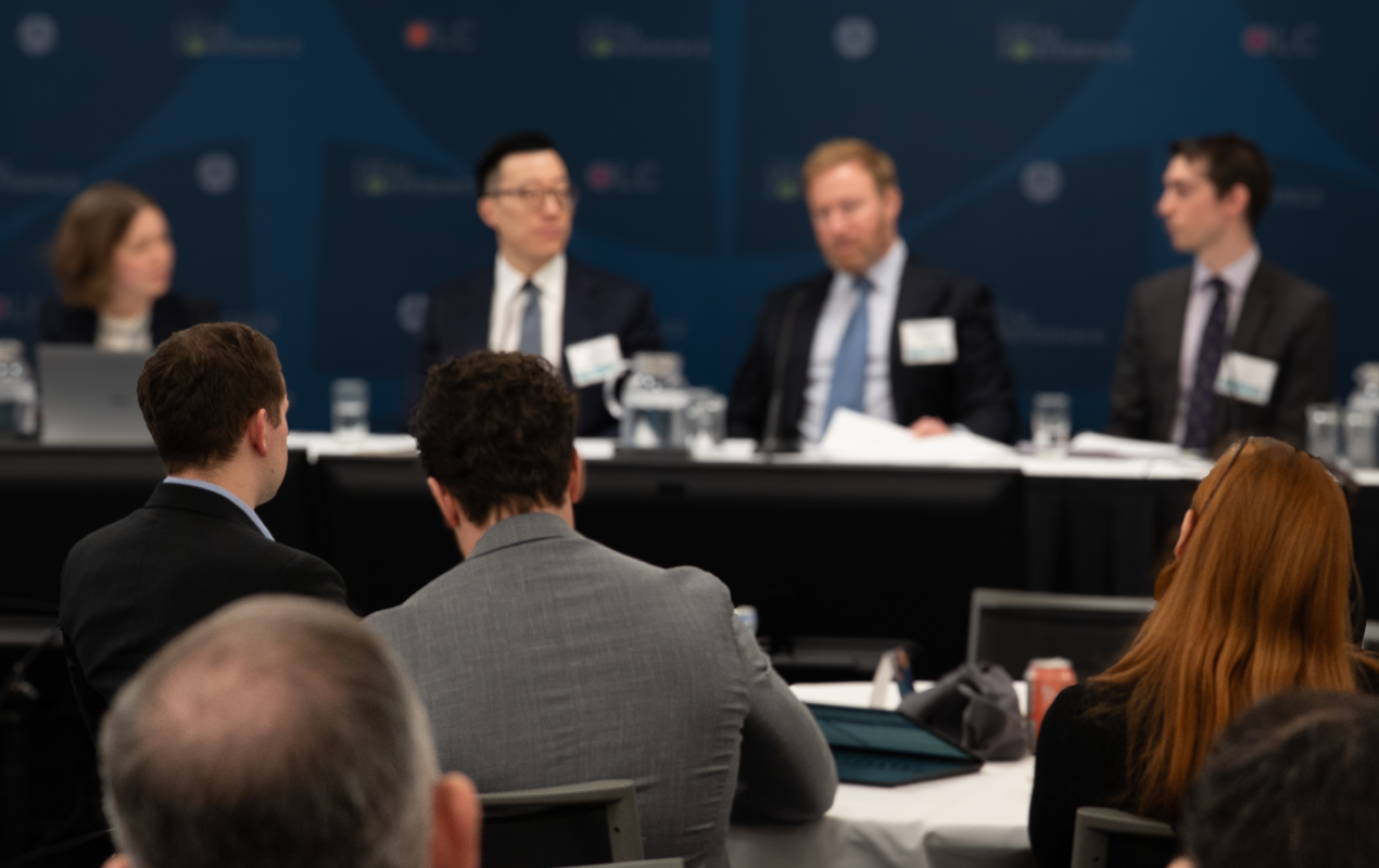 Panel of legal professionals speaking at a conference, with attendees seated in the audience.